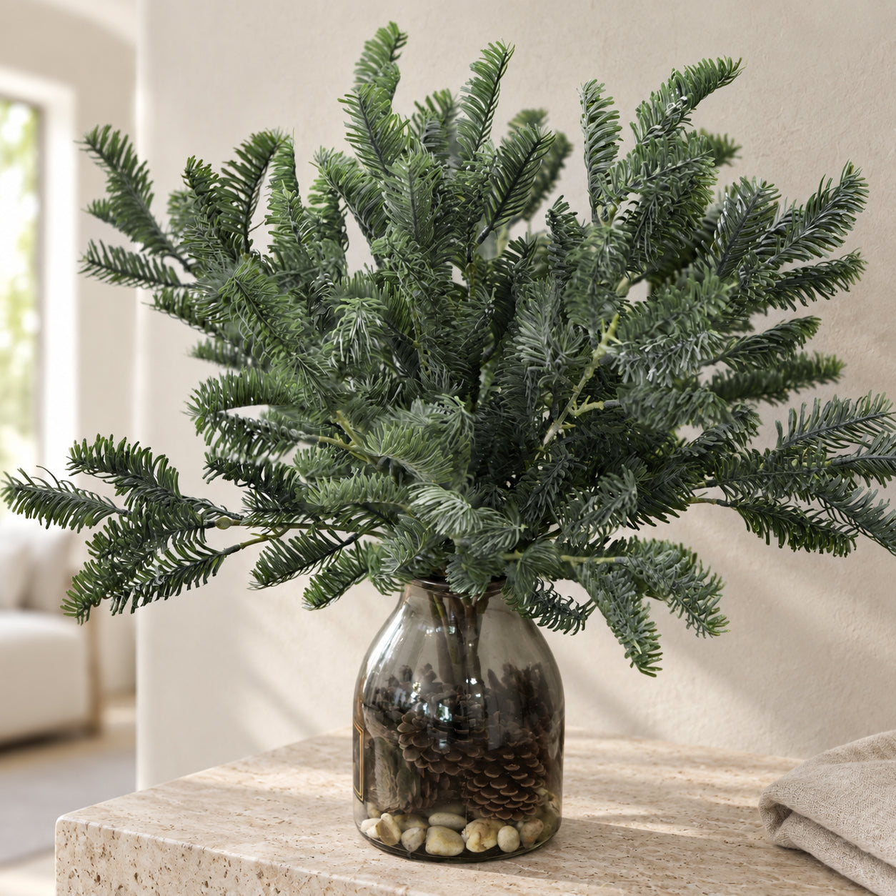 Artificial pine branches arranged in a charcoal vase for home decor
