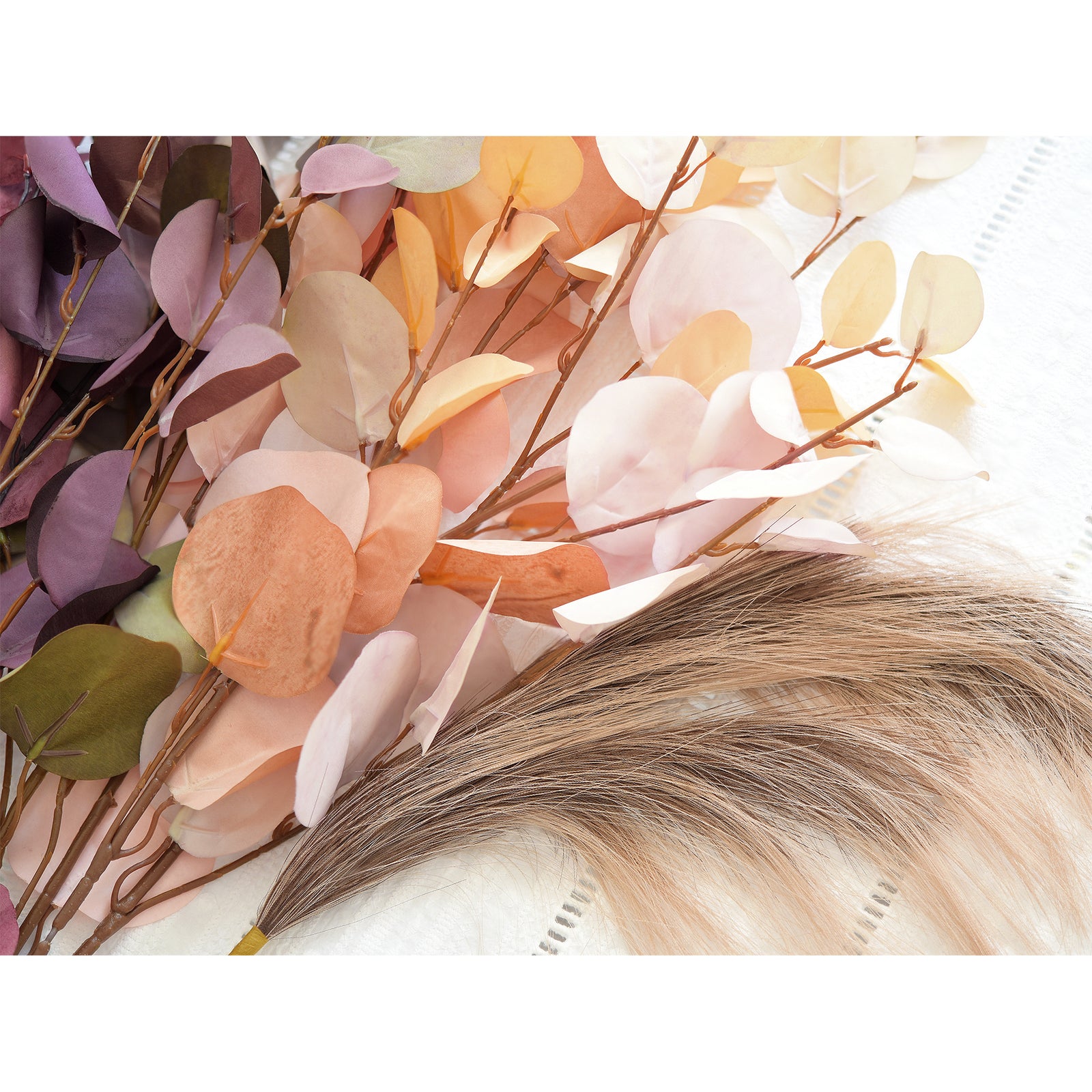 Close-up of mixed eucalyptus stems in shades of dusky pink, beige, and light brown, paired with pampas grass. The natural color palette creates a soft and tranquil decorative piece for modern and rustic interiors