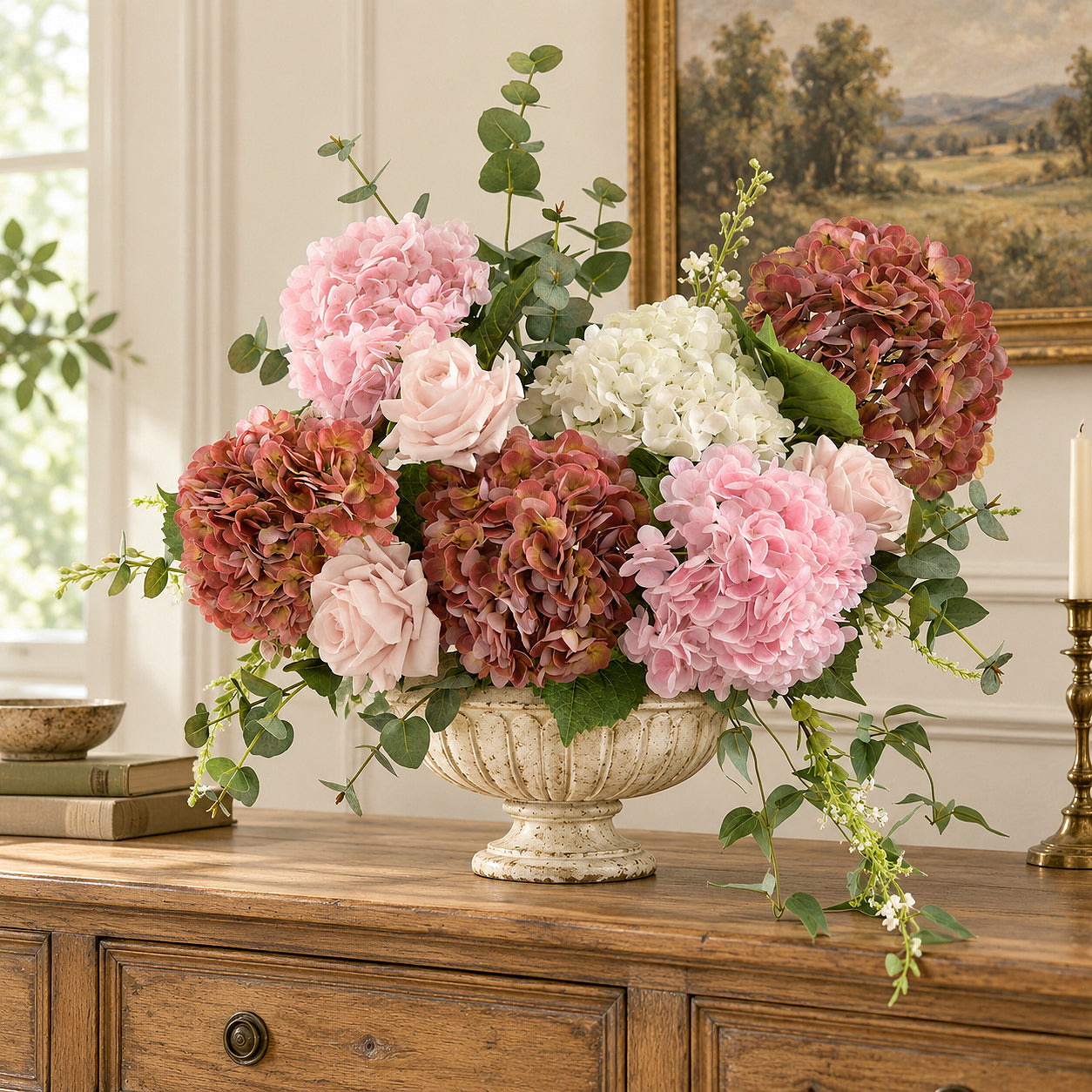Antique brick rose hydrangeas mixed with pink and white flowers in an urn on an oak sideboard.
