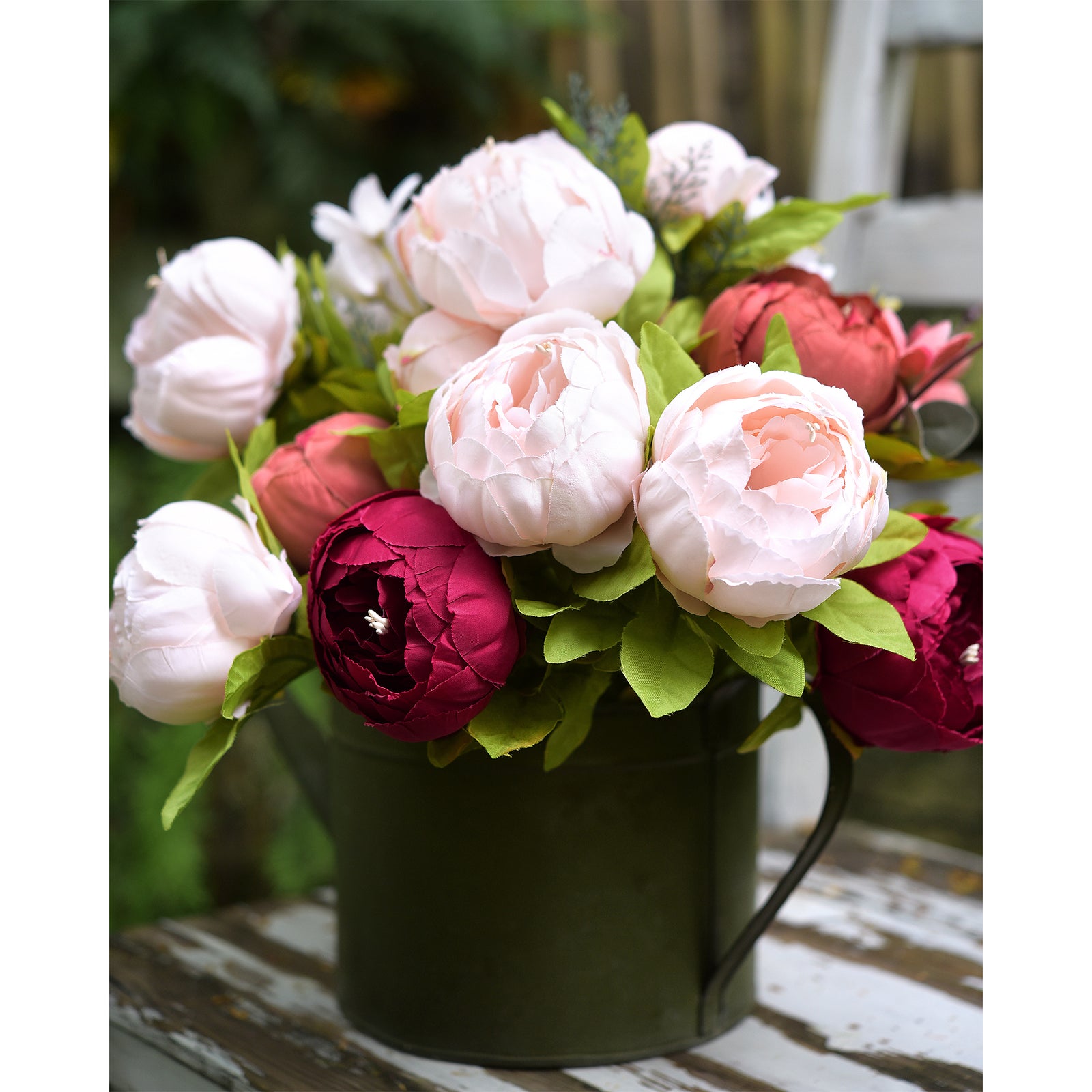 Artificial peony arrangement displayed in a dark green vase outdoors, surrounded by soft lighting for a natural look.