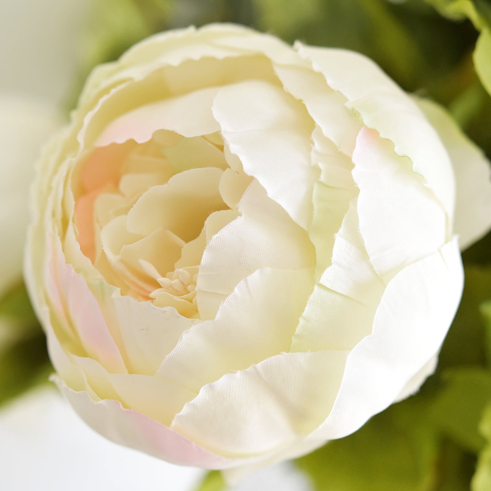 Close-up of a cream faux peony bloom showing layered silk petals and soft color detail.