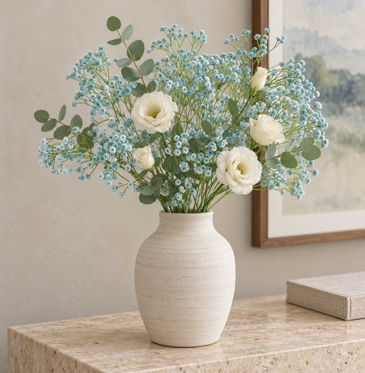 Dusty blue baby's breath with cream roses and eucalyptus in an ivory vase on a stone console.