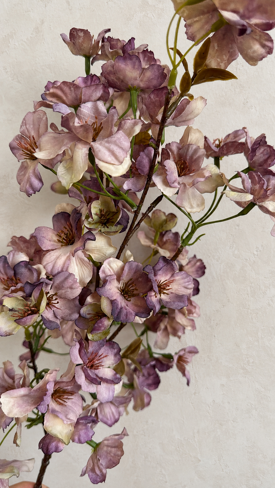 Close-up of dusty mauve artificial cherry blossoms with cream undertones and brown branch detail