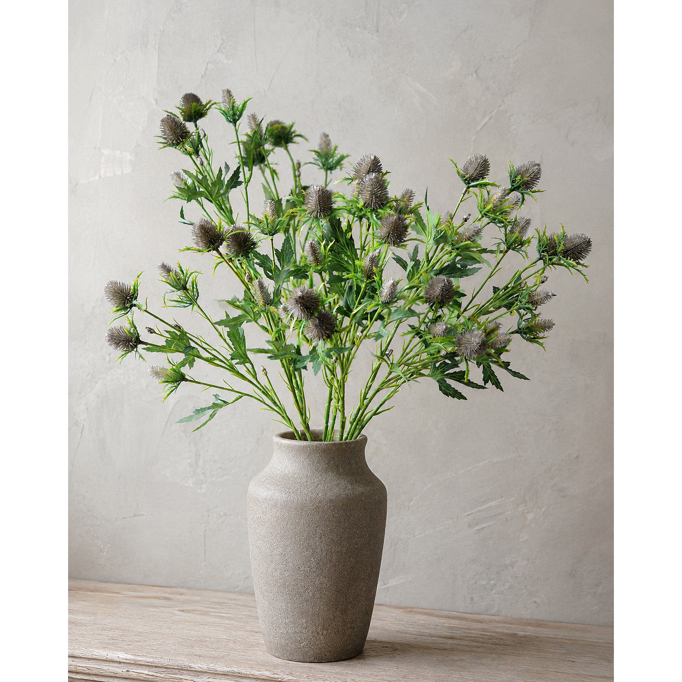 Gray-blue faux eryngium stems styled in a vase arrangement.