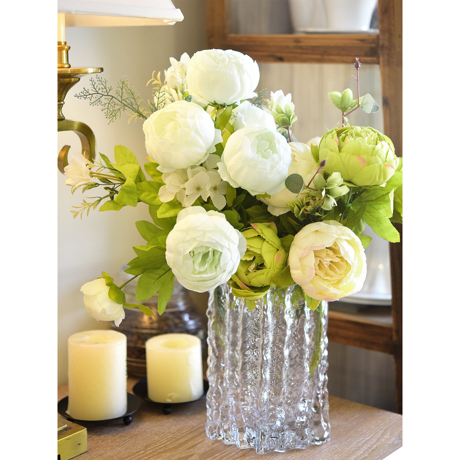 Green and white peony arrangement displayed with candles, creating a cosy and sophisticated atmosphere.