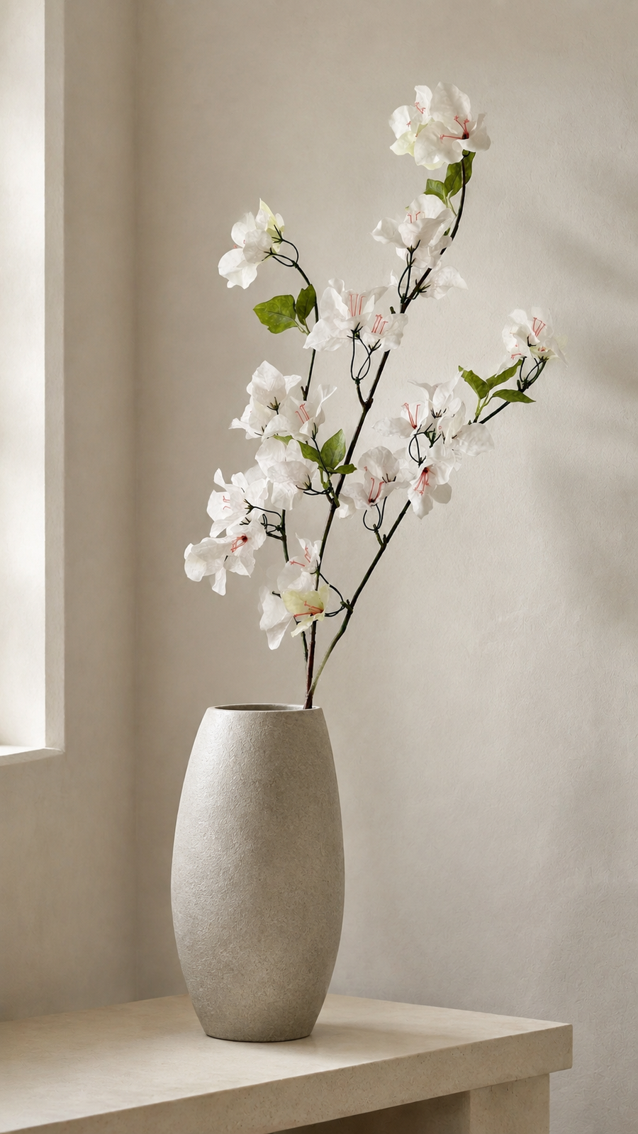 Soft White artificial bougainvillea branch styled in a tall vase in a neutral home interior