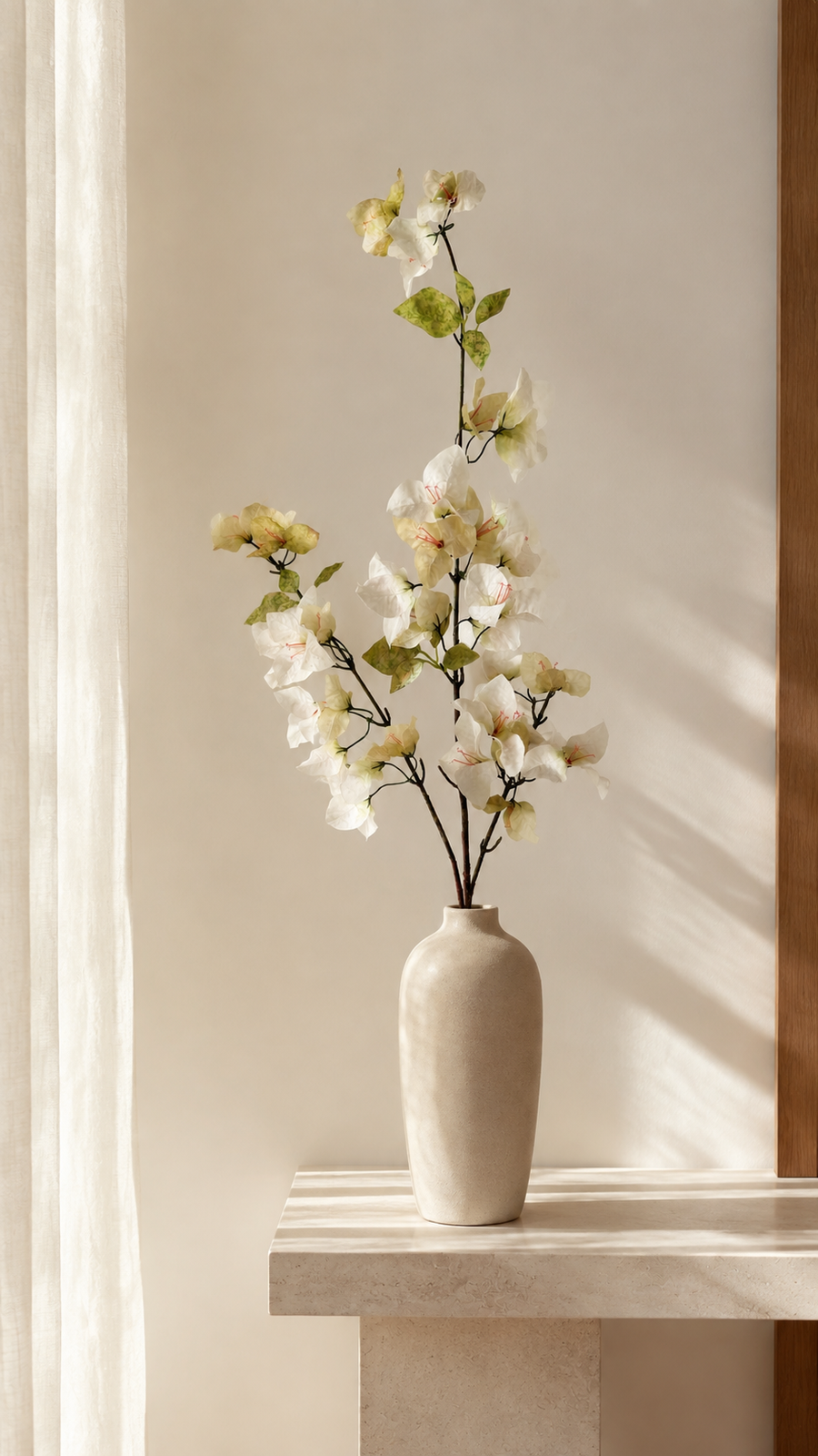 Ivory Cream artificial bougainvillea branch styled in a tall vase in a neutral home interior