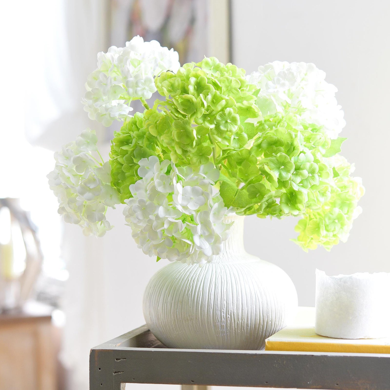 Lime green and white hydrangea stems arranged together in a ribbed vase.