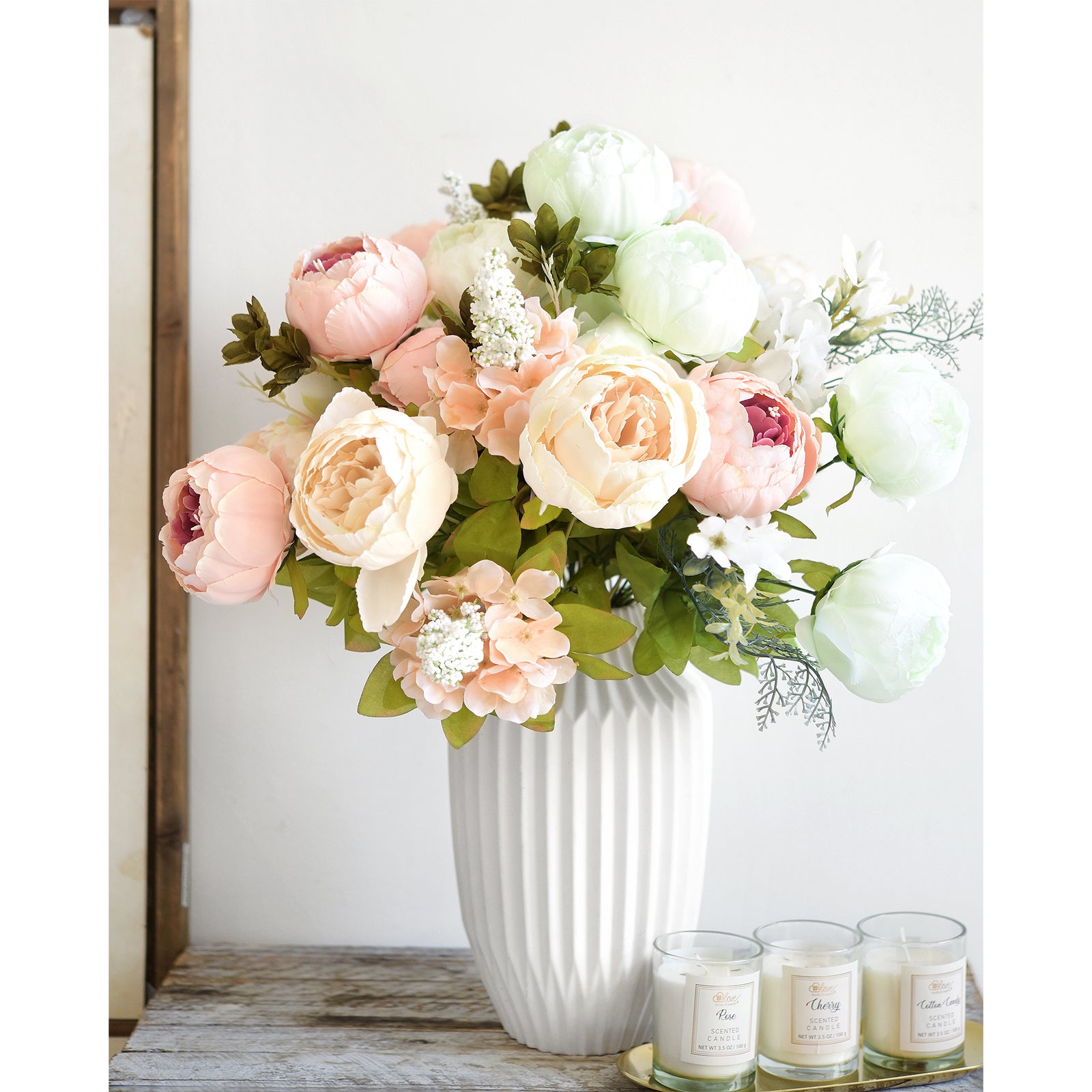 Soft blush peony arrangement with greenery, styled in a white ceramic vase, perfect for sophisticated table décor or gifting.
