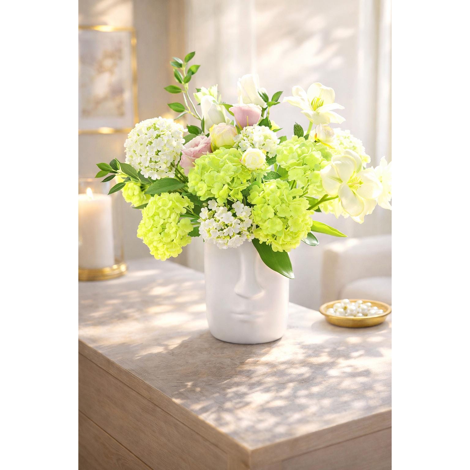 Spring green hydrangea stems styled with mixed flowers in a white vase.