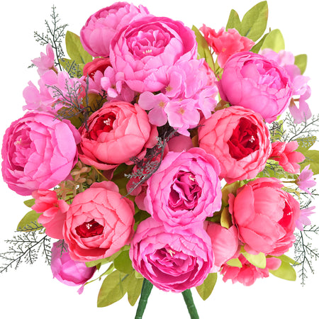 Artificial peony bouquet in vibrant hot pink, coral, and fuchsia tones with layered silk petals and lush green leaves, perfect for bold floral styling.