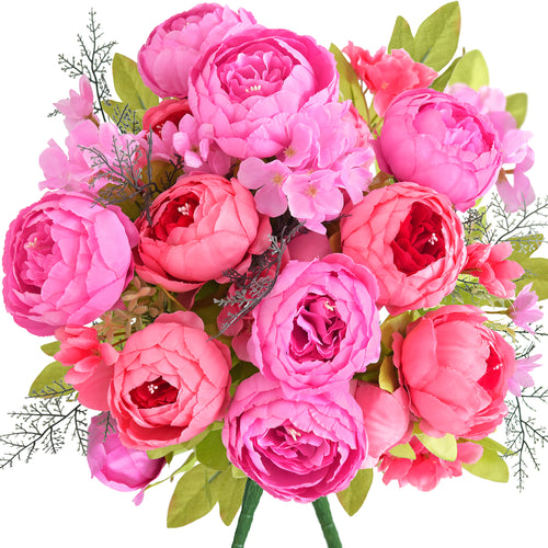 Artificial peony bouquet in vibrant hot pink, coral, and fuchsia tones with layered silk petals and lush green leaves, perfect for bold floral styling.