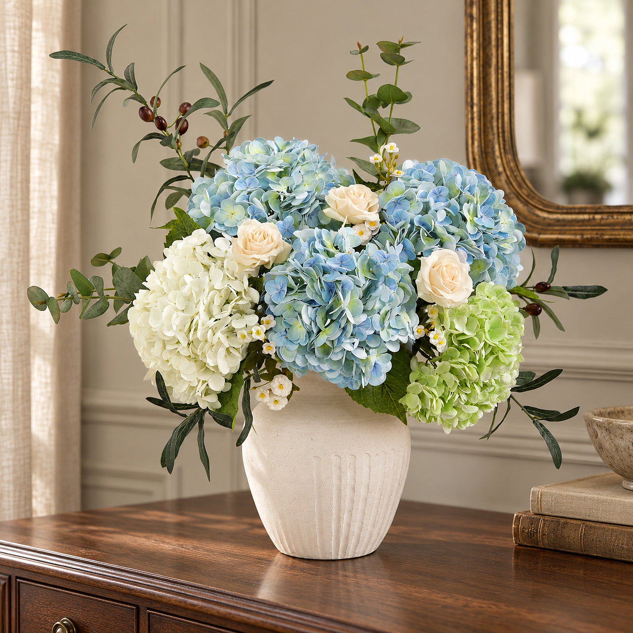 Vintage blue green hydrangeas with white flowers and cream roses in a white vase on a walnut sideboard.