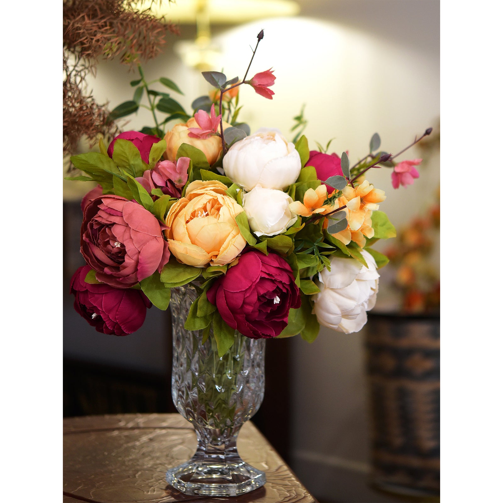 unset Whisper bouquet arranged in a striped ceramic vase with candles, styled for a wedding table centerpiece.