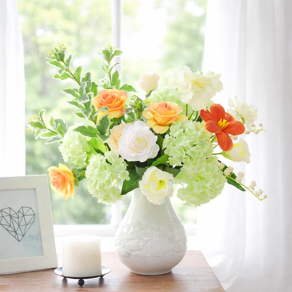 White and green hydrangea stems styled with orange and white flowers in a mixed arrangement.