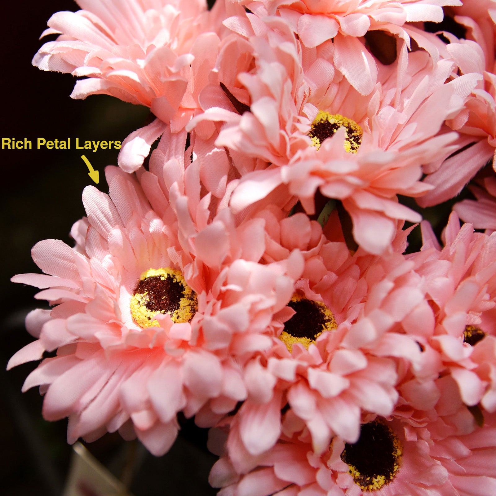 Light pink artificial silk gerbera flowers shown with layered blooms and green stems.