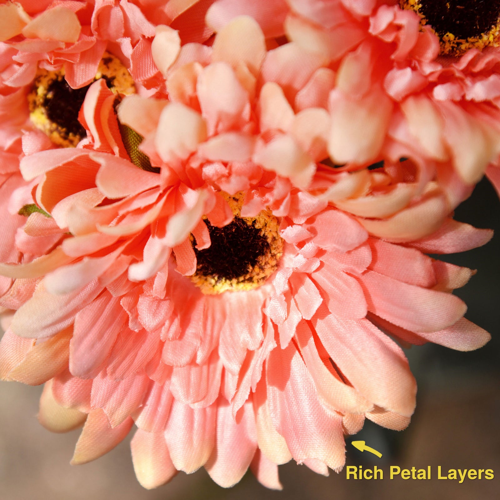 Orange pink artificial silk gerbera flowers shown with layered blooms and green stems.